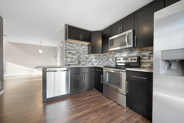 kitchen with a sink, backsplash, appliances with stainless steel finishes, and dark wood-style flooring