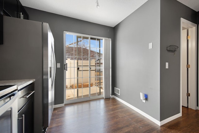 kitchen with baseboards, dark cabinets, dark wood finished floors, and freestanding refrigerator