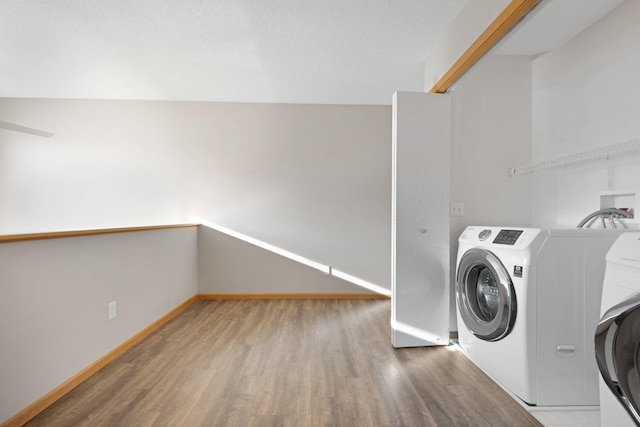 clothes washing area featuring laundry area, washer / clothes dryer, wood finished floors, and baseboards