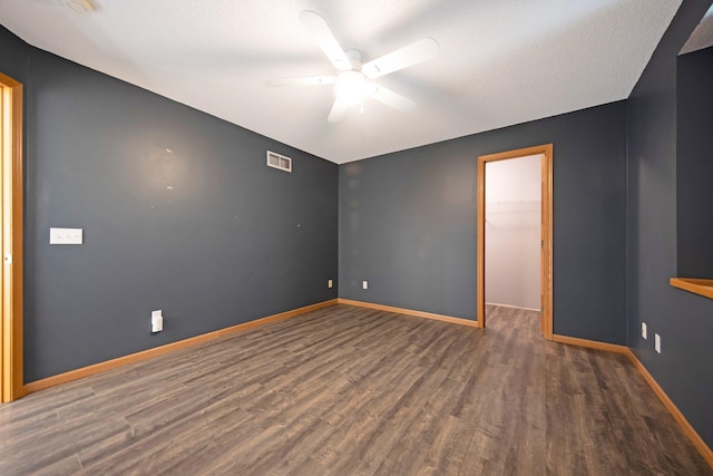 unfurnished room with ceiling fan, visible vents, baseboards, and wood finished floors