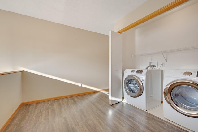 laundry area featuring laundry area, washing machine and dryer, light wood-type flooring, and baseboards