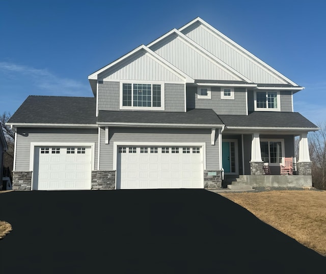 craftsman house featuring board and batten siding, a porch, a garage, stone siding, and driveway