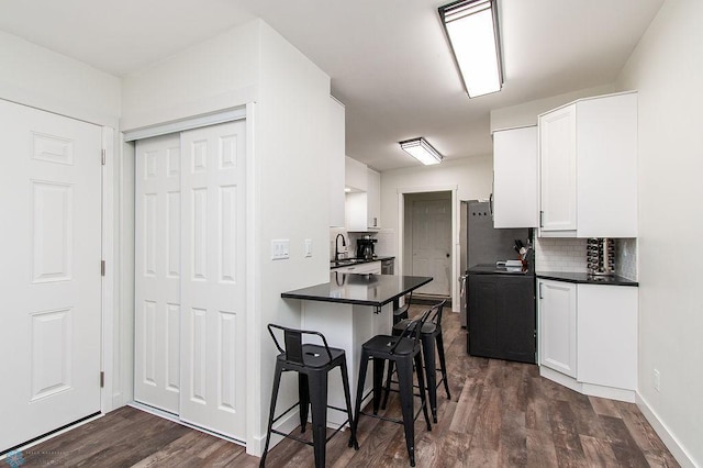 kitchen featuring stove, dark countertops, a breakfast bar, and white cabinetry