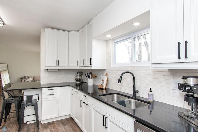 kitchen featuring a sink, decorative backsplash, a peninsula, and white cabinets