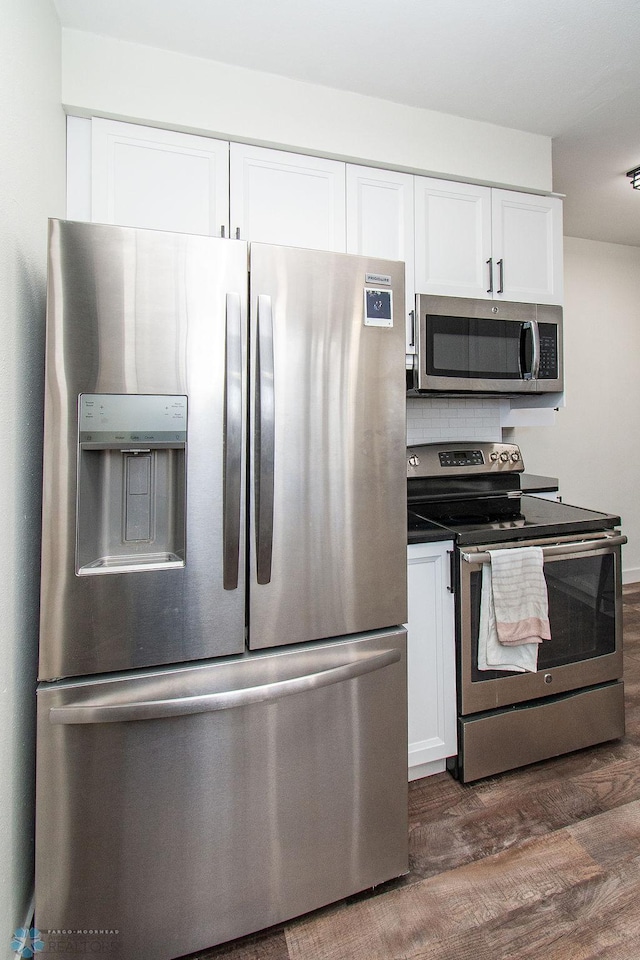 kitchen with backsplash, dark countertops, dark wood-style floors, stainless steel appliances, and white cabinets