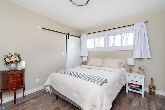 bedroom featuring baseboards, a barn door, and wood finished floors