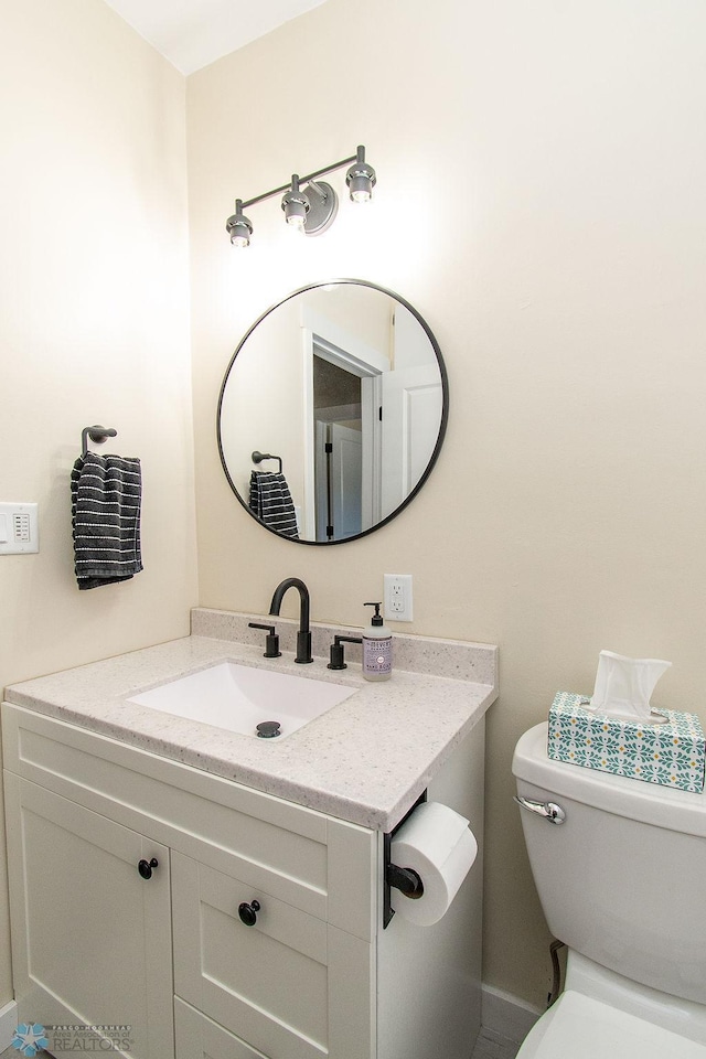 half bath featuring vanity and toilet