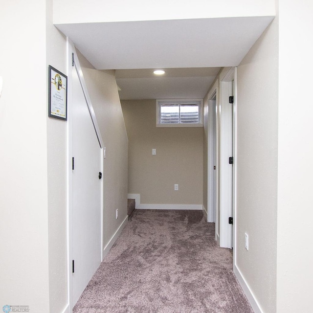 corridor featuring baseboards and carpet floors