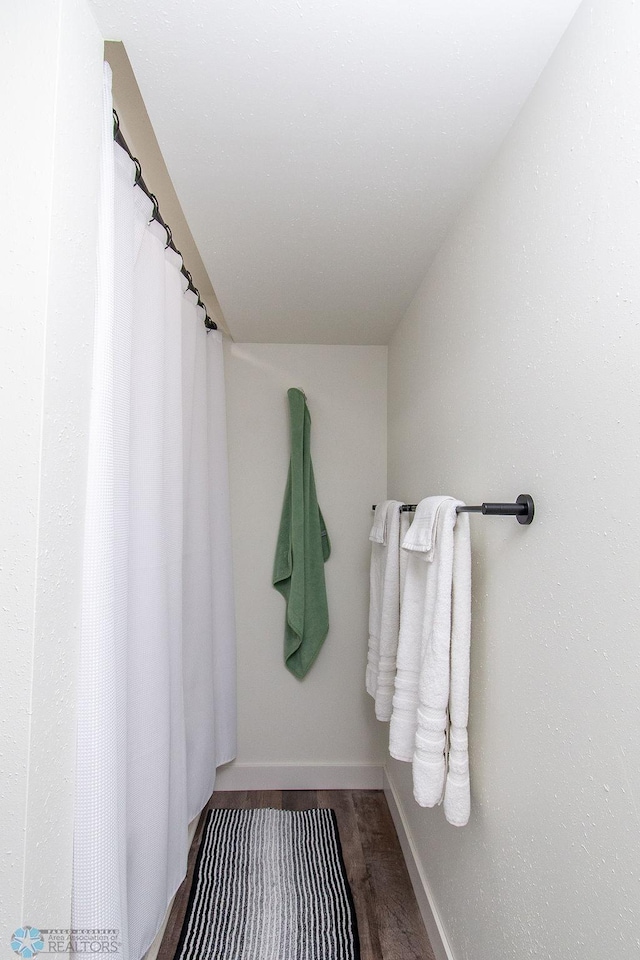 full bathroom featuring baseboards and wood finished floors