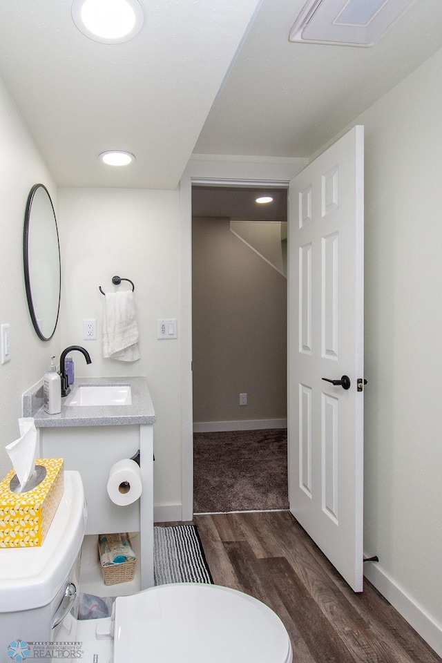 bathroom featuring vanity, toilet, wood finished floors, and baseboards