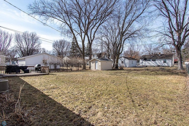 view of yard featuring fence, a wooden deck, central AC unit, an outdoor structure, and a storage unit