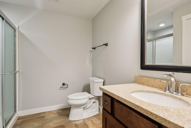 bathroom with a shower with door, toilet, vanity, and baseboards