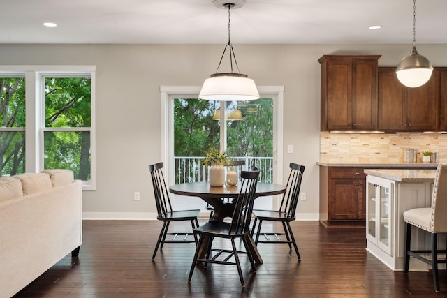 dining space with a wealth of natural light, baseboards, and dark wood finished floors