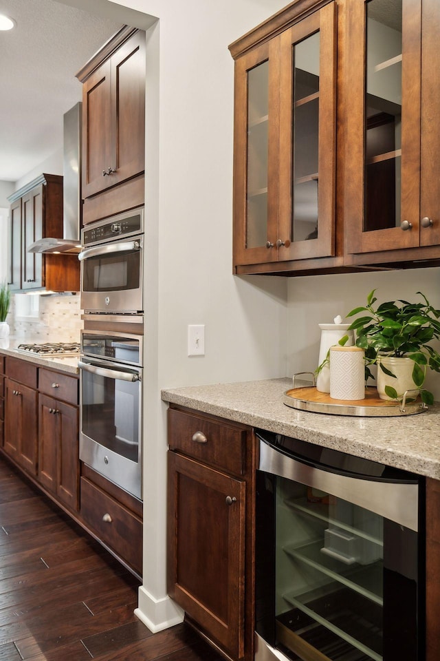 kitchen with beverage cooler, decorative backsplash, appliances with stainless steel finishes, dark wood-style floors, and wall chimney exhaust hood