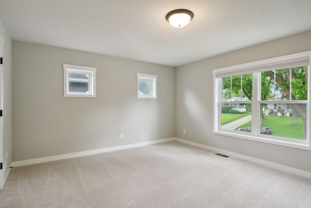 empty room featuring light carpet, visible vents, and baseboards