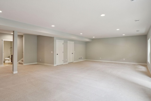 finished basement featuring stairway, visible vents, baseboards, recessed lighting, and light colored carpet