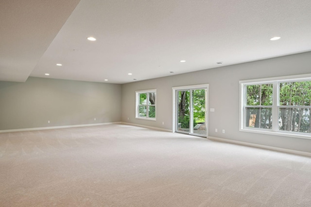 spare room with recessed lighting, light colored carpet, and baseboards