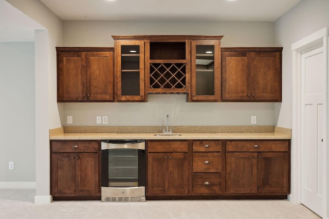 kitchen featuring light countertops, glass insert cabinets, baseboards, and a sink