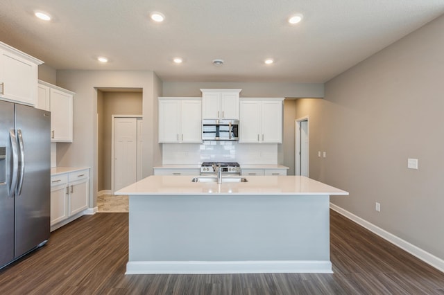 kitchen with a kitchen island with sink, a sink, tasteful backsplash, appliances with stainless steel finishes, and light countertops