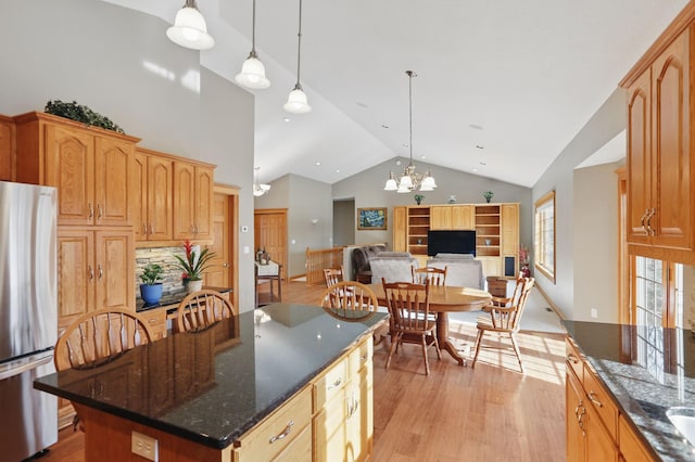 kitchen featuring light wood finished floors, freestanding refrigerator, hanging light fixtures, open floor plan, and a center island