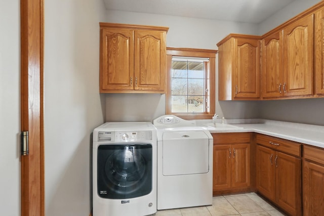 clothes washing area with light tile patterned flooring, cabinet space, washer and dryer, and a sink