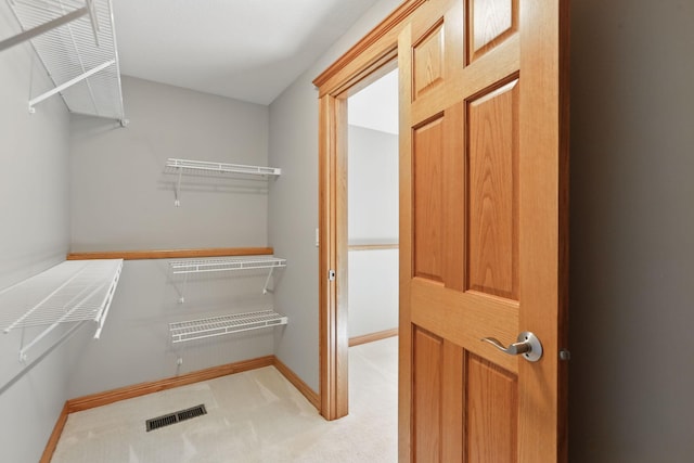 walk in closet with visible vents and light colored carpet