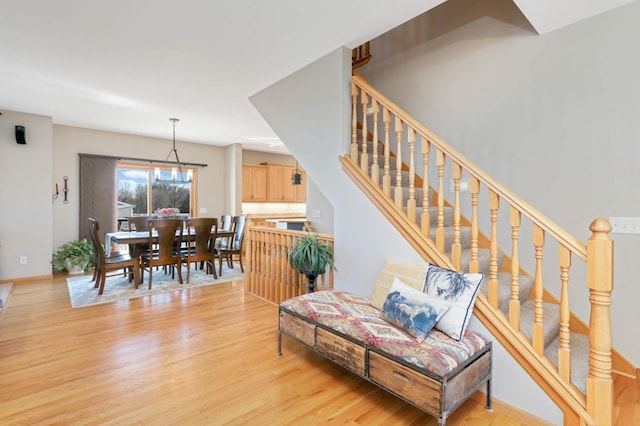 living area with light wood-style flooring, stairs, and baseboards