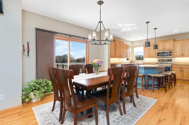 dining space with recessed lighting, light wood-type flooring, and an inviting chandelier