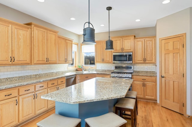 kitchen featuring light brown cabinets, appliances with stainless steel finishes, a breakfast bar, and a sink