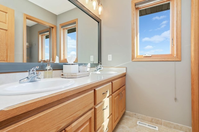 bathroom with tile patterned flooring, double vanity, visible vents, and a sink