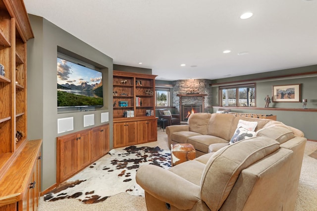 living area with a stone fireplace, recessed lighting, and light carpet