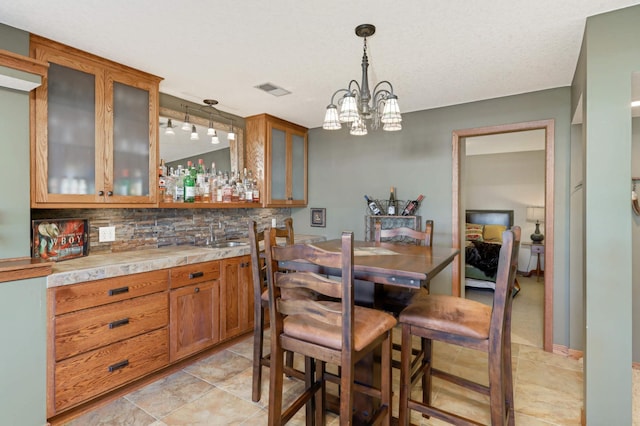 dining space with indoor wet bar, a notable chandelier, and visible vents