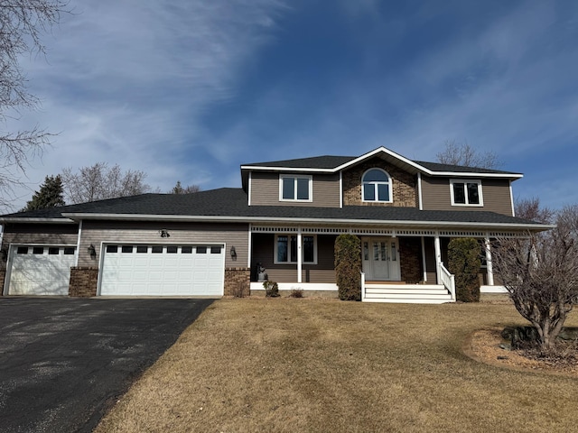 view of front facade featuring brick siding, a porch, a front yard, a garage, and driveway