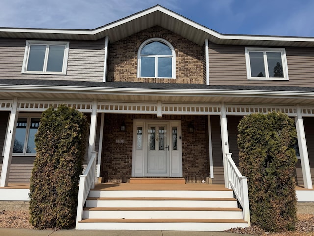 view of front facade with brick siding and covered porch