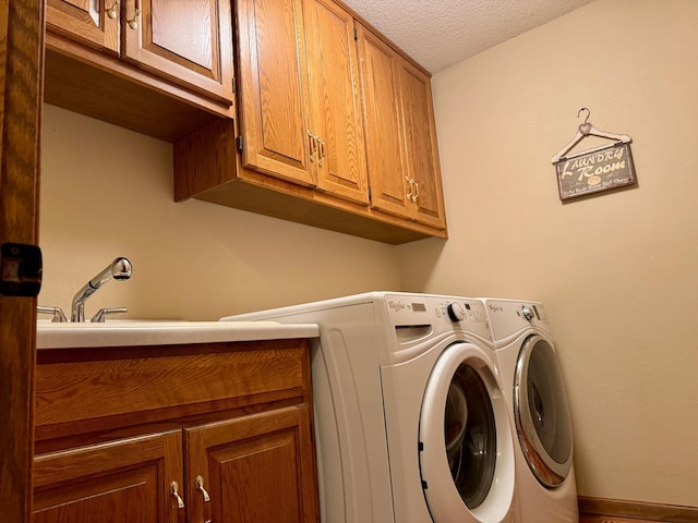 laundry area featuring a sink, cabinet space, a textured ceiling, and separate washer and dryer