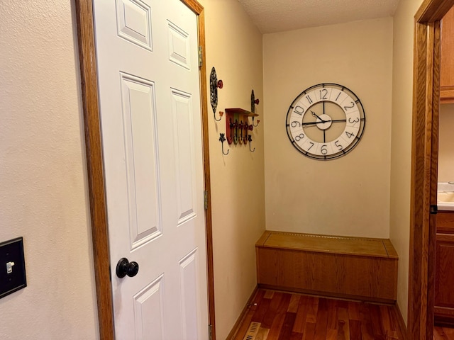 hallway featuring a textured ceiling and dark wood finished floors