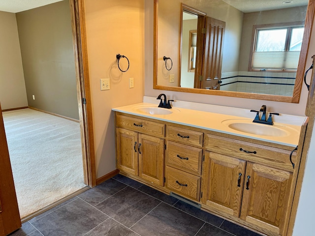 bathroom featuring a sink, visible vents, baseboards, and double vanity