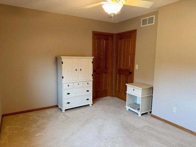 unfurnished bedroom with visible vents, baseboards, light colored carpet, and ceiling fan