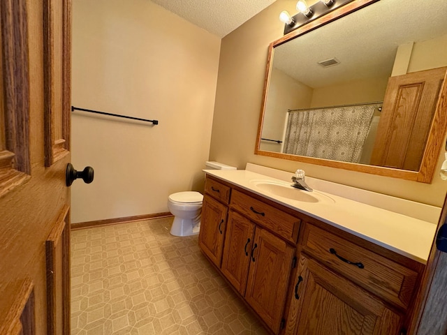 bathroom featuring tile patterned floors, toilet, a textured ceiling, baseboards, and vanity