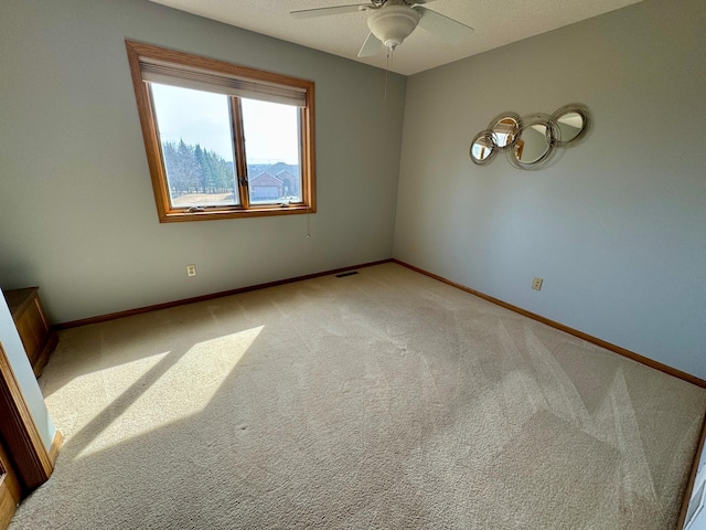 unfurnished room featuring visible vents, light colored carpet, a ceiling fan, and baseboards