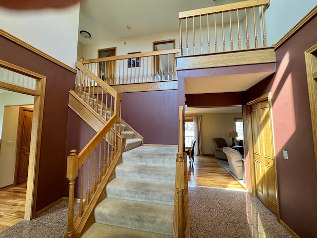 staircase featuring a high ceiling, wood finished floors, and baseboards