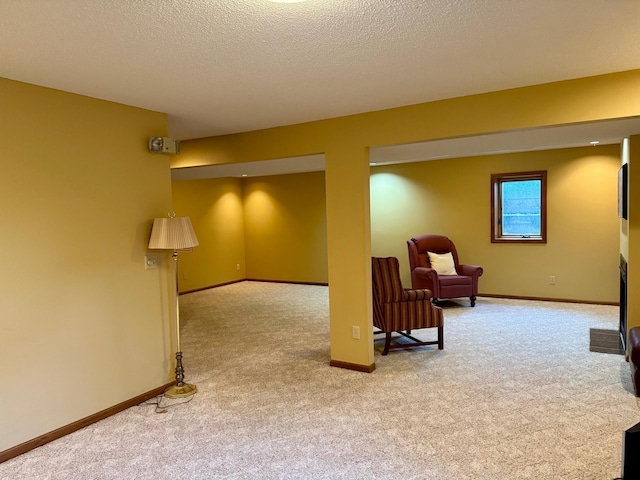 below grade area with a fireplace, carpet, baseboards, and a textured ceiling