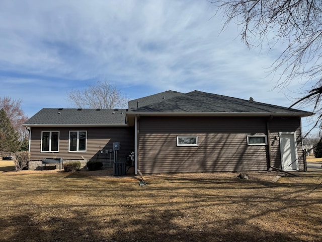 back of house with a yard and roof with shingles