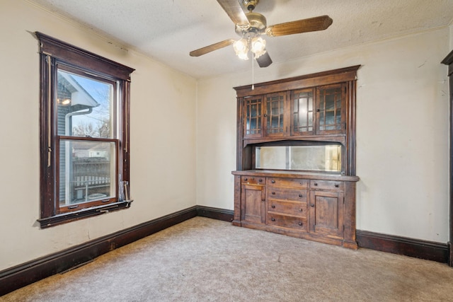 carpeted empty room featuring baseboards, a textured ceiling, and ceiling fan