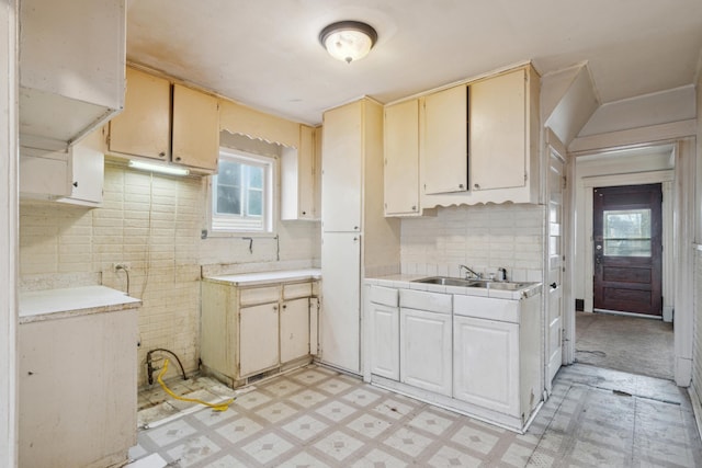 kitchen featuring tile countertops, light floors, backsplash, and a sink