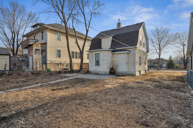 rear view of property featuring a gambrel roof, fence, a shingled roof, a chimney, and a patio area