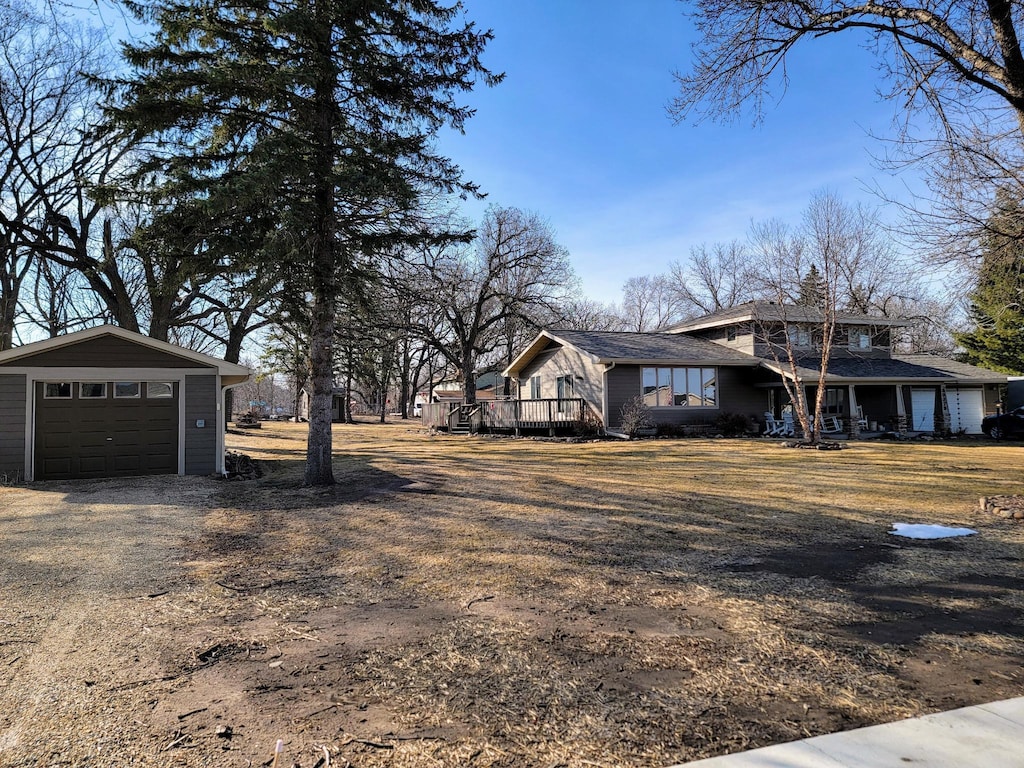 view of yard with a garage, driveway, an outdoor structure, and a deck