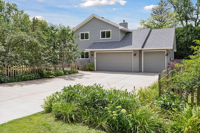 view of front of house with driveway, an attached garage, a chimney, a shingled roof, and a fenced front yard