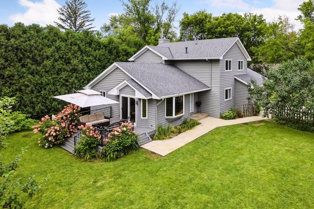 rear view of house with a wooden deck, a lawn, a chimney, and a shingled roof