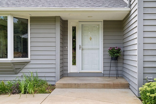 entrance to property featuring roof with shingles